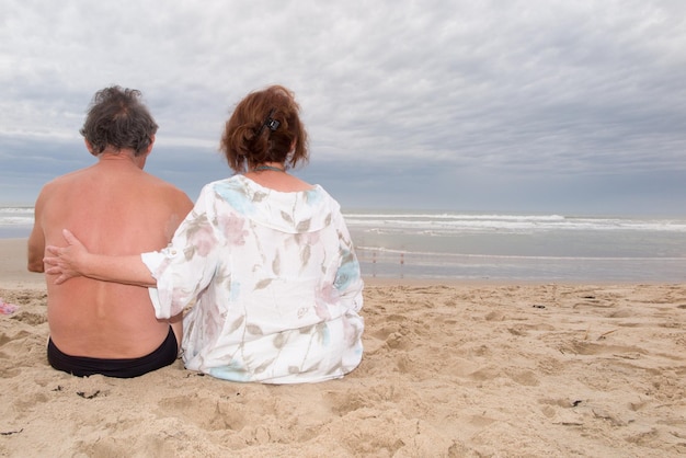 Widok pary siedzącej na plaży z tyłu