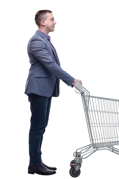 Widok pełnej długości przystojnego młodego mężczyzny stojącego z wózkiem na zakupy i patrzącego na kamerę
