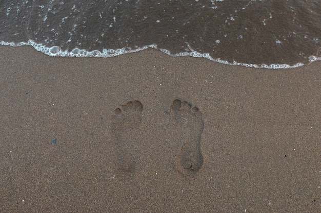 Widok piasku na plaży w lecie z śladami stóp