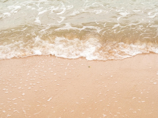 widok pod dużym kątem. Fale oceanu uderzają w plażę lub brzeg i pęcherzyki powietrza. Mokry piasek, woda morska