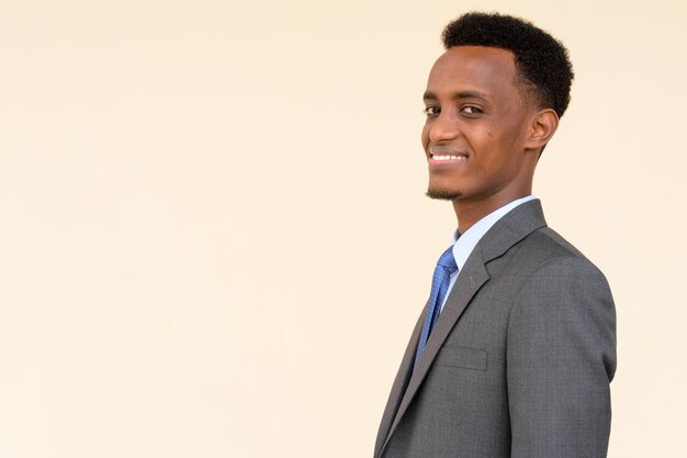 Widok profilu przystojnego afrykańskiego biznesmena uśmiechającego się na prostym tle