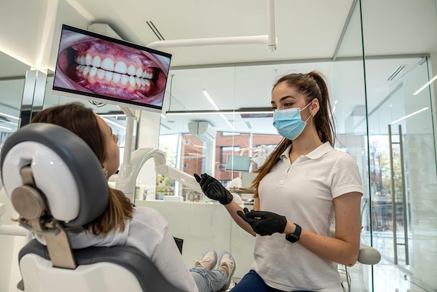 Widok przez ramię dentysty badającego zęby pacjentki w klinice dentystycznej