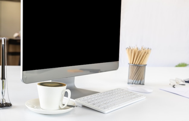 Widok pulpitu komputera pokój biurowy z pustego ekranu i biały kubek czarnej kawy, długopis, ołówek, schowek. Korzystanie jako koncepcja biznesu i pracy.