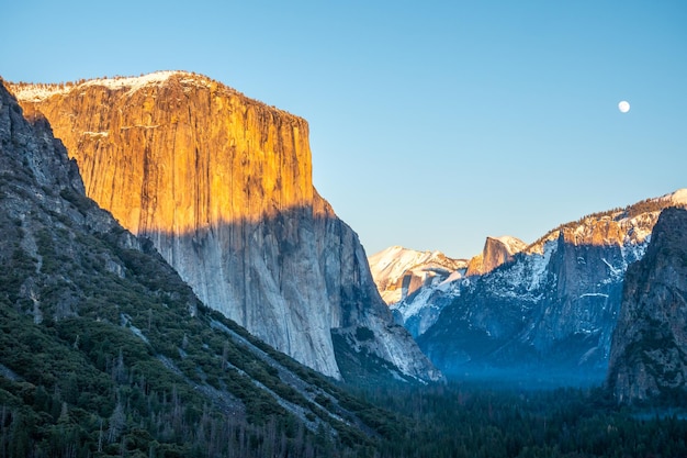 Widok tunelu Yosemite Valley o zachodzie słońca w zimie. Pełnia księżyca. El Capitan i Half Dome. Kalifornia, USA. Upływ czasu