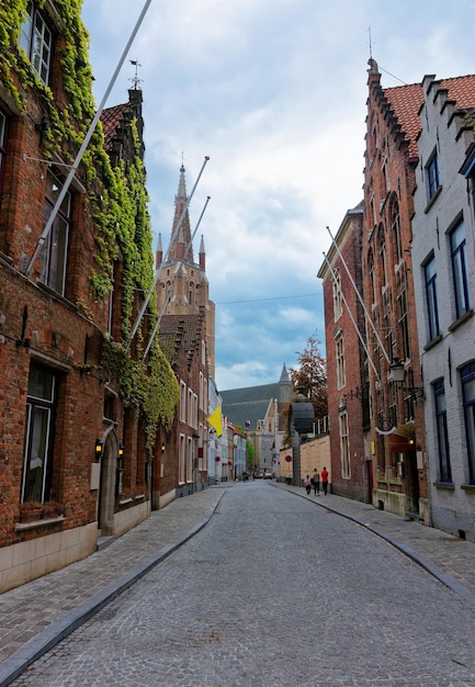 Widok ulicy na kościół Matki Boskiej w średniowiecznej starówce w Brugge, Belgia. Ludzie w tle