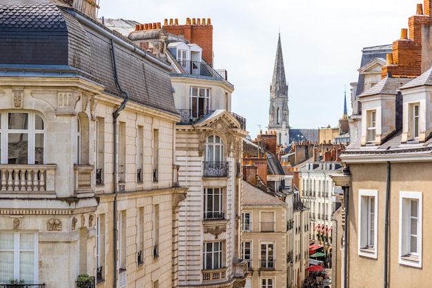 Widok ulicy na piękne budynki mieszkalne i wieżę kościoła w mieście Nantes w słoneczny dzień we Francji