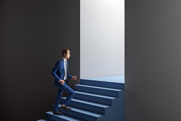 Widok z boku atrakcyjnego, przemyślanego młodego europejskiego biznesmena chodzącego w abstrakcyjnym otworze betonowej ściany z niebieskimi schodami i makietą miejsca Koncepcja możliwości i sukcesu drzwi