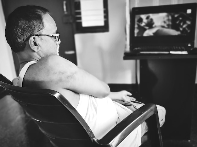 Widok z boku człowieka oglądającego telewizję siedzącego w domu