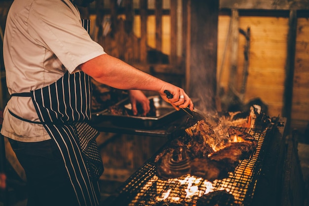 Widok z boku człowieka przygotowującego mięso na grillu
