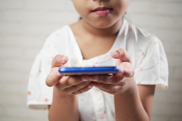 Widok z boku dłoni dziecka trzymającego inteligentny telefon w pomieszczeniu
