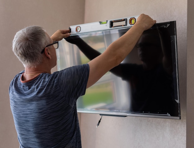 Widok z boku dojrzałego technika instalującego telewizor w domu