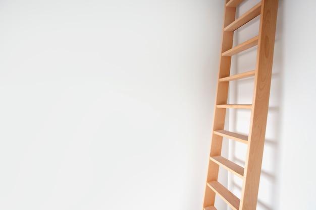 Widok z boku drewnianej drabiny opartej o białą ścianę nowoczesny design stylowe schody w jasnym pokoju