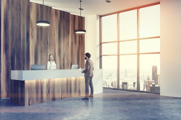 Widok z boku drewnianej i białej recepcji stojącej w nowoczesnej hali biurowej z betonową podłogą. Ludzie. Renderowania 3D makieta stonowanych obrazów