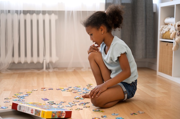 Zdjęcie widok z boku dziewczyny układającej puzzle na podłodze