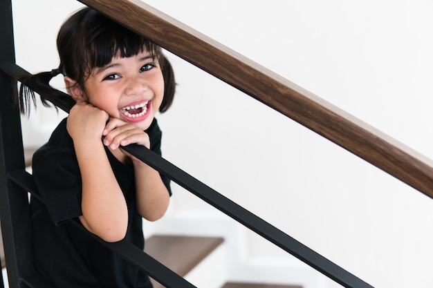 Widok z boku klatki schodowej w domu. Po schodach wspina się mała dziewczynka.
