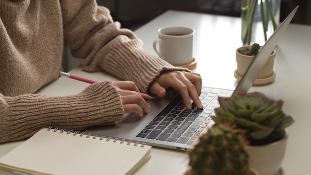 Widok z boku kobiecych rąk pisania na klawiaturze laptopa