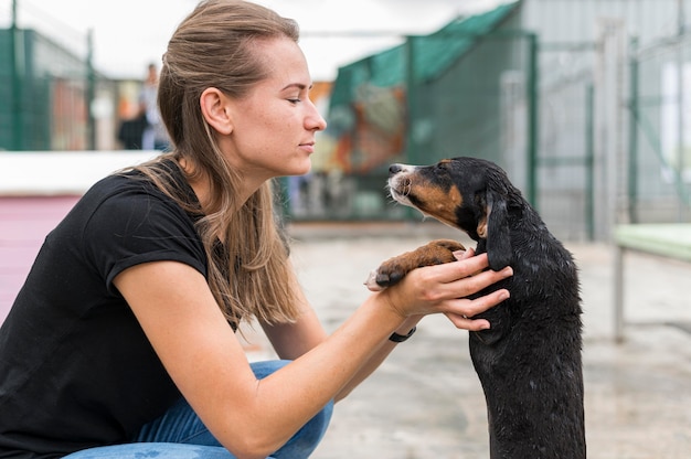 Widok z boku kobiety i psa ratowniczego w schronisku adopcyjnym