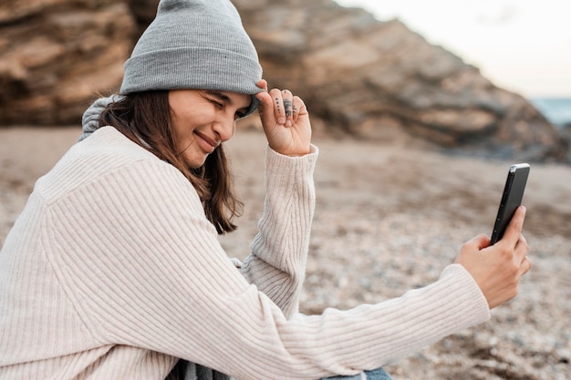 Zdjęcie widok z boku kobiety przy selfie na plaży