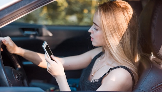 Widok z boku kobiety używającej telefonu podczas jazdy samochodem