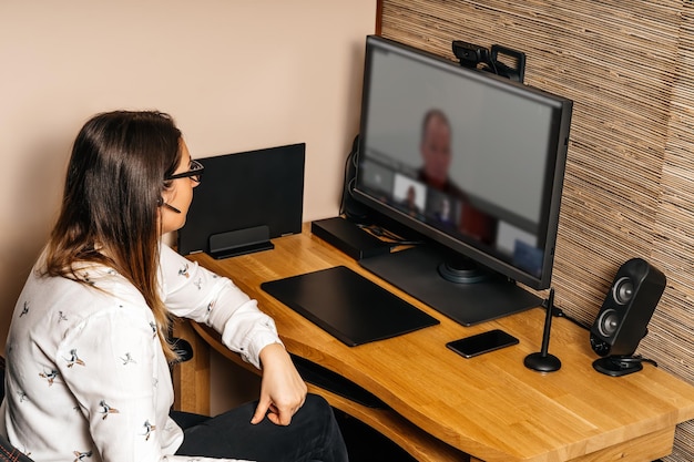 Zdjęcie widok z boku kobiety wideo konferencji przez komputer w domu