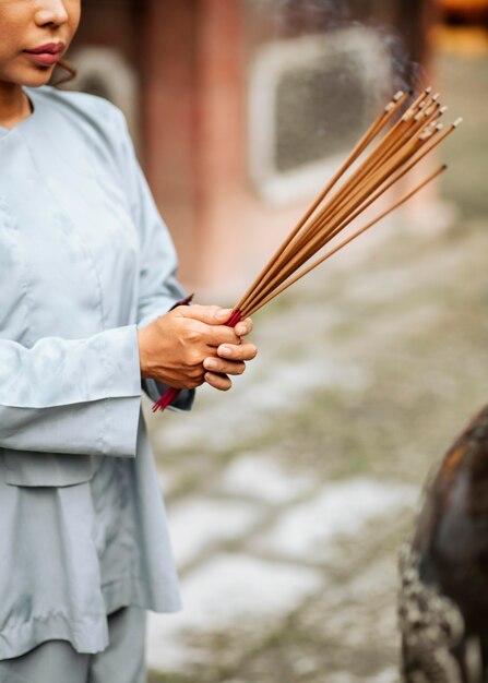 Widok z boku kobiety z płonącym pakietem kadzidła w świątyni