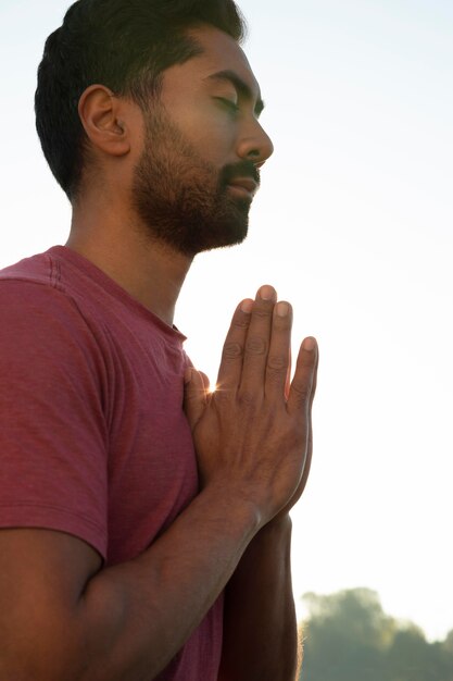 Zdjęcie widok z boku mężczyzny medytującego na zewnątrz