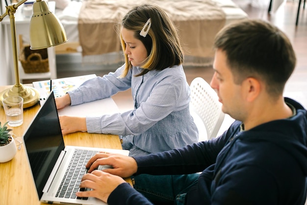 Widok z boku mężczyzny używającego laptopa siedzącego obok dziewczyny w domu