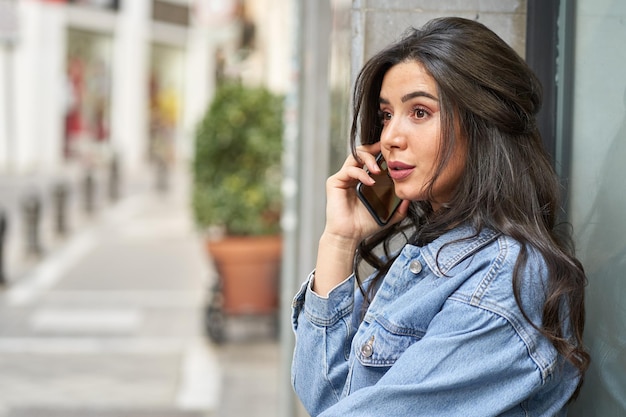 Widok z boku młodej kobiety rozmawiającej telefonem w mieście