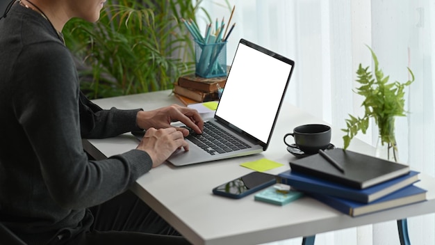 Widok z boku młody człowiek freelancer za pomocą informacji wyszukiwania laptopa w domowym biurze.