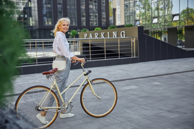 Widok z boku na całej długości portret atrakcyjnej blondynki z retro rowerem w pustym centrum miasta city