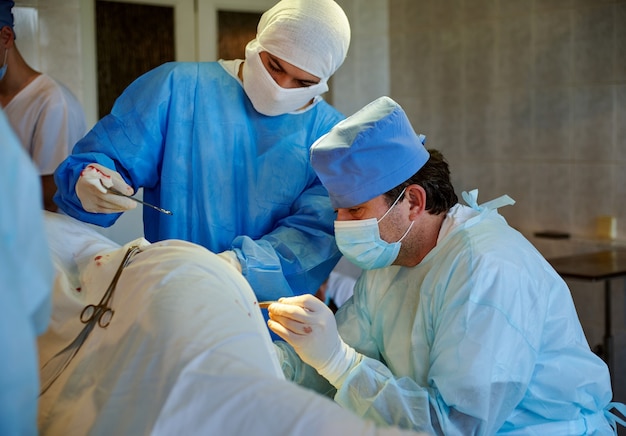 Widok z boku na chirurga wykonującego operację, obok jego asystenta