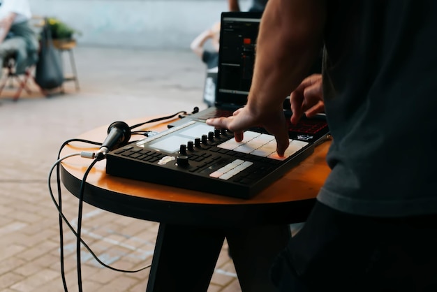 Widok z boku nierozpoznawalnego muzyka ulicznego beatmakera grającego bity hip-hopowe na kontrolerze midi automatu perkusyjnego na festiwalu selektywnym na świeżym powietrzu