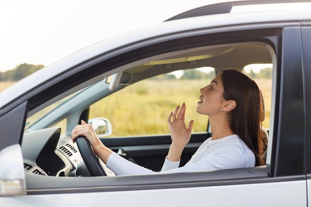 Widok z boku portret przyjemnie wyglądającej kobiety siedzącej na siedzeniu kierowcy i patrzącej w lustro na jej makijaż ciemnowłosa kobieta ubrana w białą koszulę podróżująca samotnie