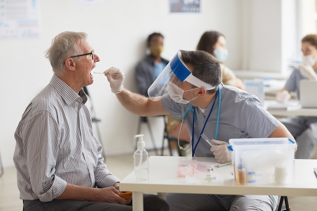 Widok z boku portret starszego mężczyzny biorącego test na covid w centrum szczepień lub klinice, miejsce kopiowania