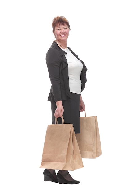 Widok z boku portret szczęśliwej starszej kobiety pozującej z torbą na zakupy, patrząc na kamerę i uśmiechniętej