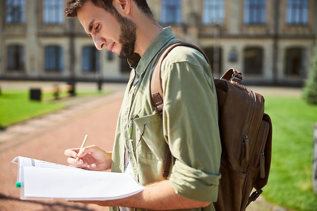 Widok Z Boku Studenta Z Ołówkiem W Dłoni Wpatrującego Się W Skoroszyt