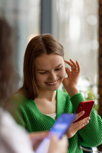 Zdjęcie widok z boku uśmiechniętych przyjaciół ze smartfonem