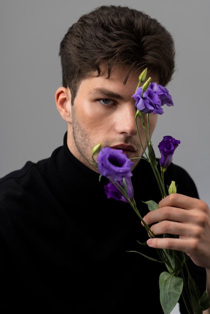 Zdjęcie widok z boku wrażliwy mężczyzna z fioletowymi kwiatami