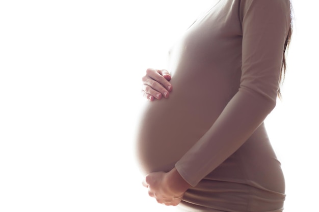 Widok z boku z bliska zdjęcie ciężarnej kobiety stojącej przed oknem Sylwetka w ciąży