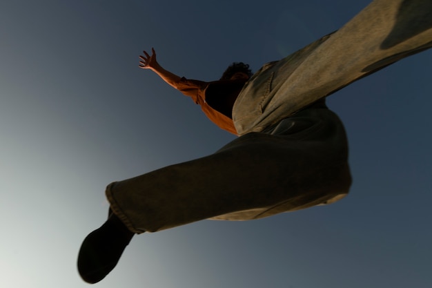 Zdjęcie widok z dołu sylwetka człowieka skoki o zachodzie słońca