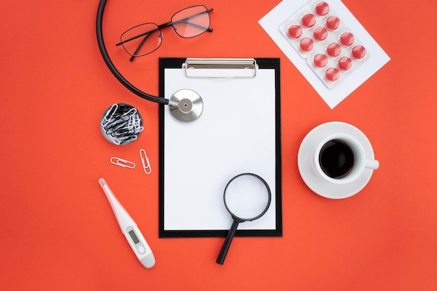 Widok z góry akcesoria medyczne na czerwonym tle Tablet do notatek okulary stetoskop pigułki leki