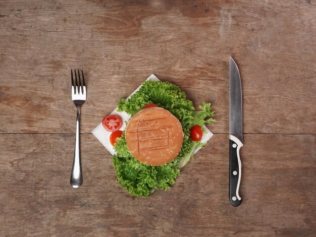 Widok z góry Appetite Burger na drewnianym stole Nóż i widelec leżą na stole Skopiuj miejsce