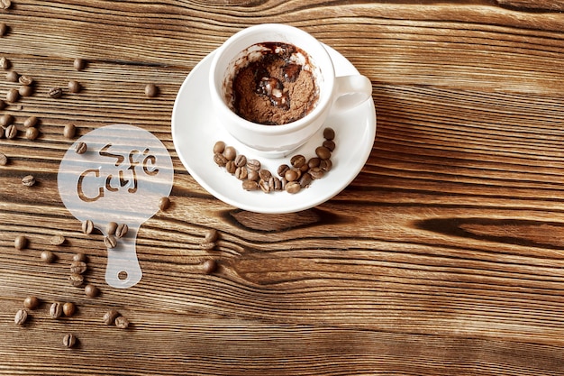 Zdjęcie widok z góry ceramicznego kubka gorącej kawy cappuccino latte z rysunkiem obrazka kawiarnianego szablonu z tworzywa sztucznego, cynamonu lub kakao na piance mlecznej, ziarna kawy na drewnianym stole, miejsce na kopię