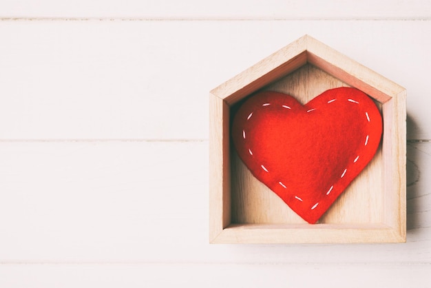Widok z góry czerwone serce tekstylne w domu na drewnianym tle. Koncepcja domu słodki dom. Walentynki.