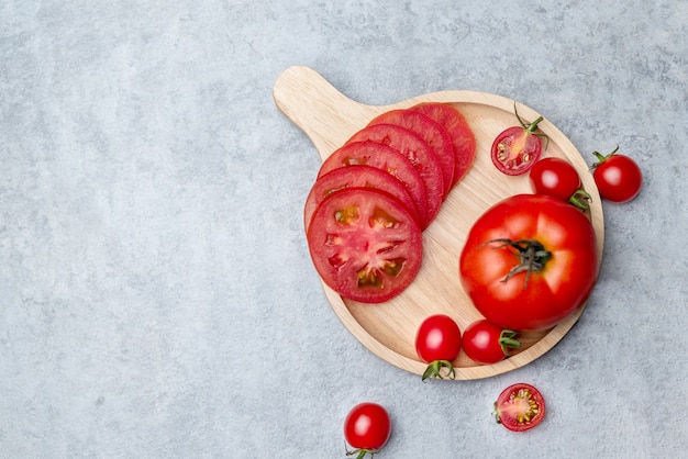 Widok z góry czerwonego pomidora w plasterkach umieścić na drewnianym naczyniu i umieścić na marmurowym stole.