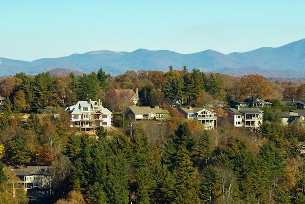 Widok z góry drogich domów mieszkalnych wysoko na szczycie wzgórza między żółtymi jesiennymi drzewami na przedmieściach Karoliny Północnej Amerykańskie domy marzeń jako przykład rozwoju nieruchomości na przedmieściach USA
