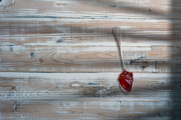 Widok z góry Dżem truskawkowy w białej łyżce nad drewnianym stołem