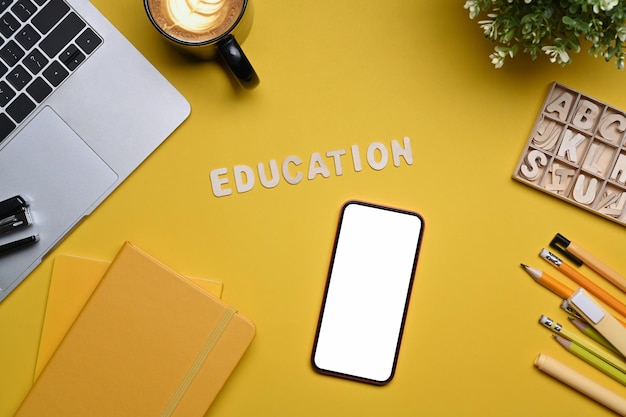 Zdjęcie widok z góry inteligentny telefon laptop i artykuły papiernicze na żółtym tle powrót do koncepcji szkoły