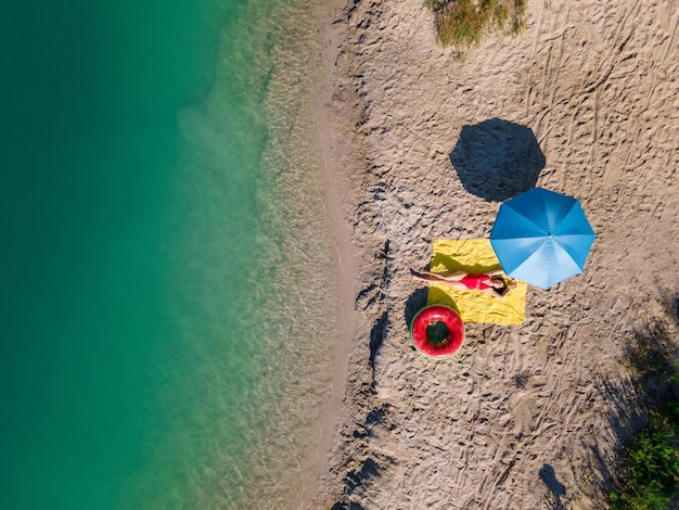 Widok z góry kobieta opalająca się na piaszczystej plaży niebieskie jezioro woda kopia przestrzeń