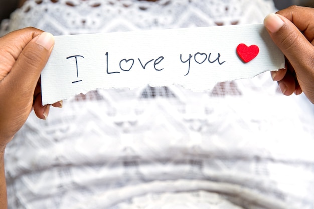 Widok z góry kobiety afro w białej sukni trzymającej papierową wiadomość kocham cię. Koncepcja Walentynki.